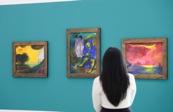 Eine Frau steht vor drei Nolde Werken.